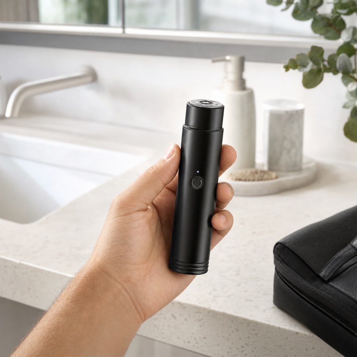 Compact black TrimPod electric shaver held in a modern bathroom